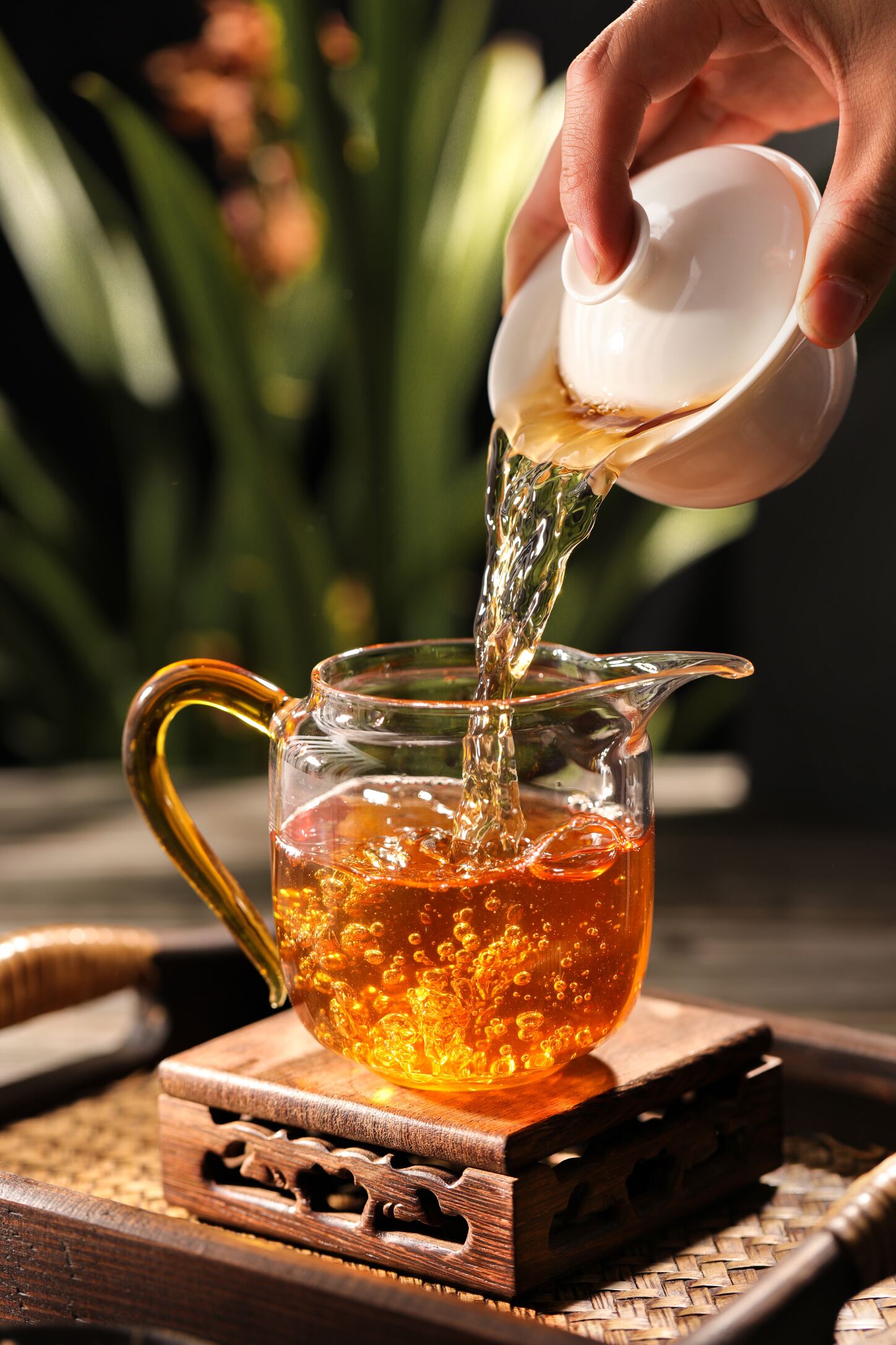 hand holding a tea pot pouring tea in a cup