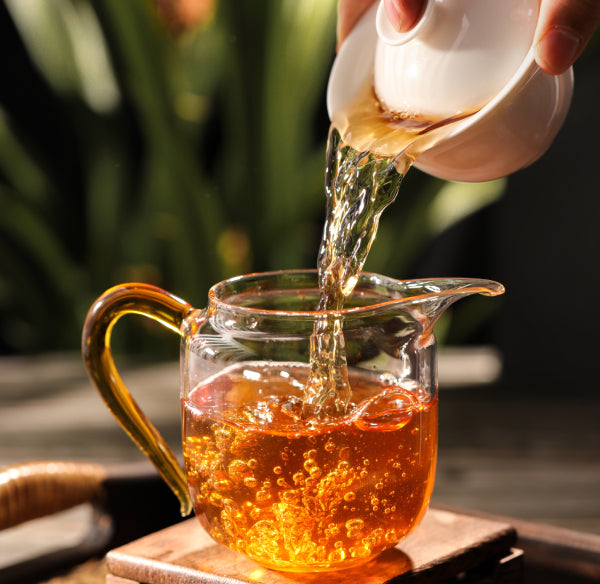 hand holding a tea pot pouring tea in a cup