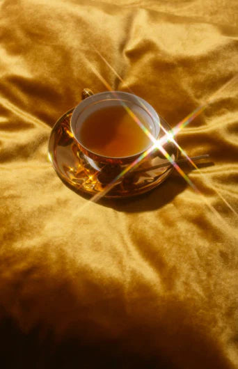 gold tea cup and saucer set on golden sheet